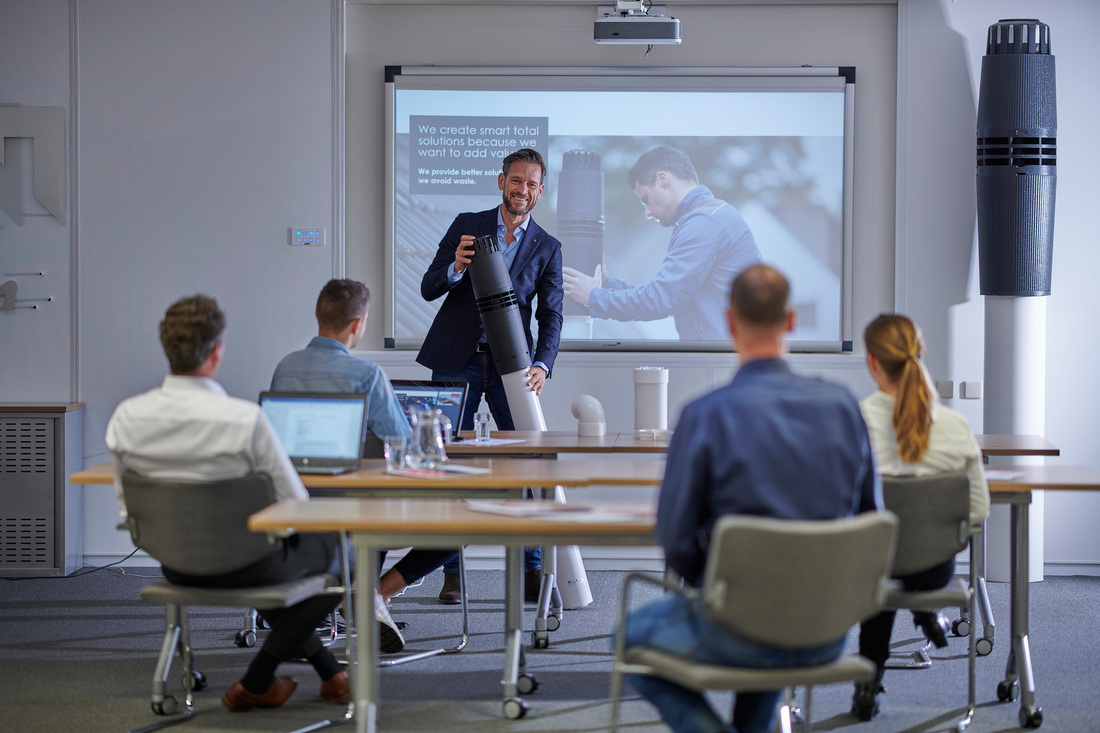 Een man die een presentatie geeft aan een publiek tijdens een product training over rookgasafvoersystemen