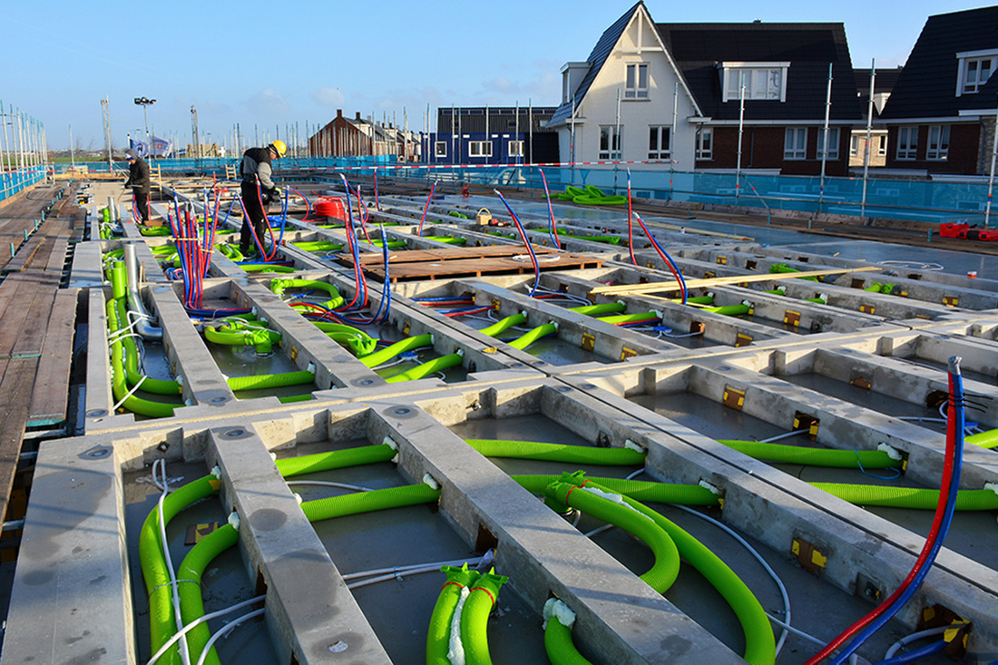 Bouwplaats waar mannen bezig zijn om Air Excellent ventilatiekanalen in de fundering te leggen